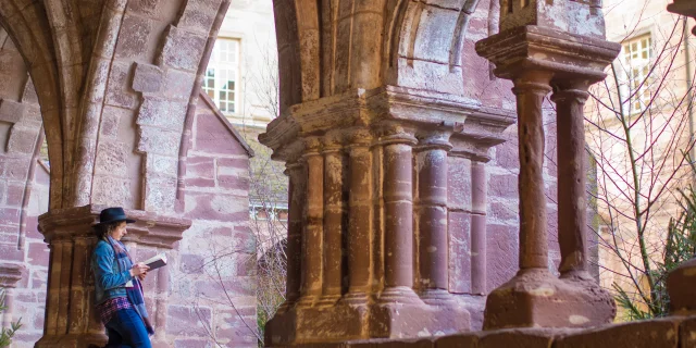 Une femme profite du calme du cloître de l'abbaye de Luxeuil-les-Bains pour lire un livre - Vosges du Sud