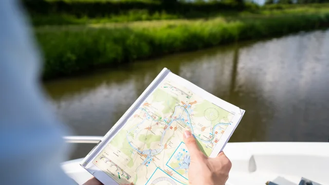 Un homme consulte la carte de navigation sur la Saône à bord de son bateau - Tourisme fluvial sur la Saône - Vesoul-Val de Saône