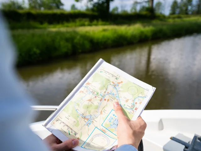 Un homme consulte la carte de navigation sur la Saône à bord de son bateau - Tourisme fluvial sur la Saône - Vesoul-Val de Saône