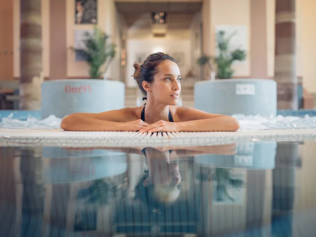 Une femme profite d'un moment bien-être et détente dans le jacuzzi des thermes de Luxeuil-les-Bains - Vosges du Sud