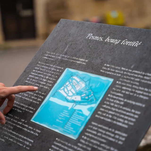 Une personne lit un panneau explicatif et plan de situation de la Cité de Caractère de Pesmes (Plus Beaux Villages de France) - Vallée de l'Ognon