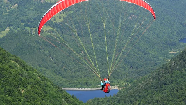 Un homme fait du parapente au Ballon d'Alsace et admire les paysages notamment le lac d'Alfeld et le lac de Sewen - Vosges du Sud