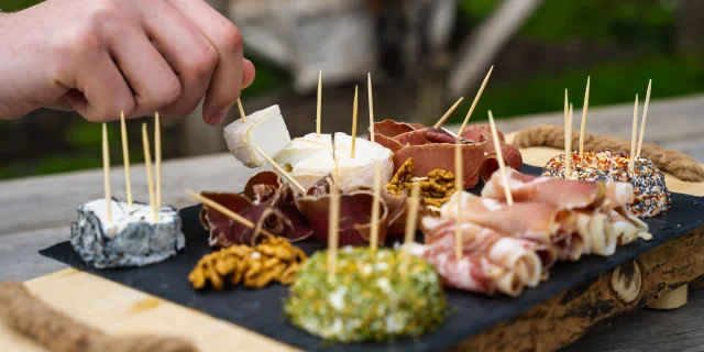 Un homme déguste un plateau de fromages de chèvres et charcuterie produit par la chèvrerie des bois pâturés de Servance - Vosges du Sud