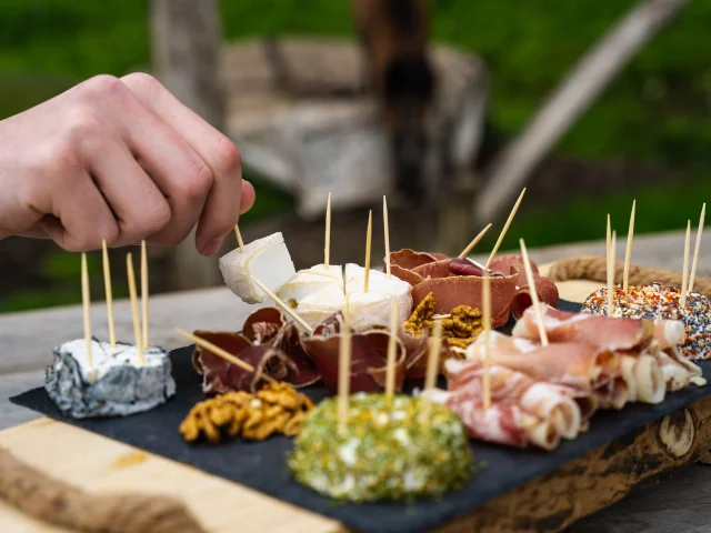 Un homme déguste un plateau de fromages de chèvres et charcuterie produit par la chèvrerie des bois pâturés de Servance - Vosges du Sud