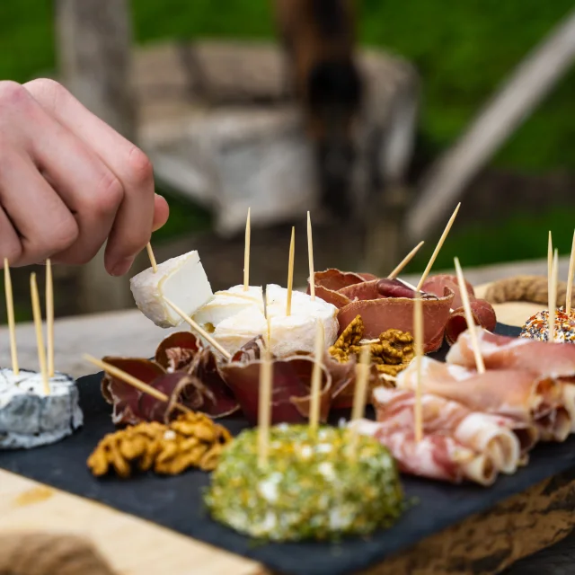 Un homme déguste un plateau de fromages de chèvres et charcuterie produit par la chèvrerie des bois pâturés de Servance - Vosges du Sud