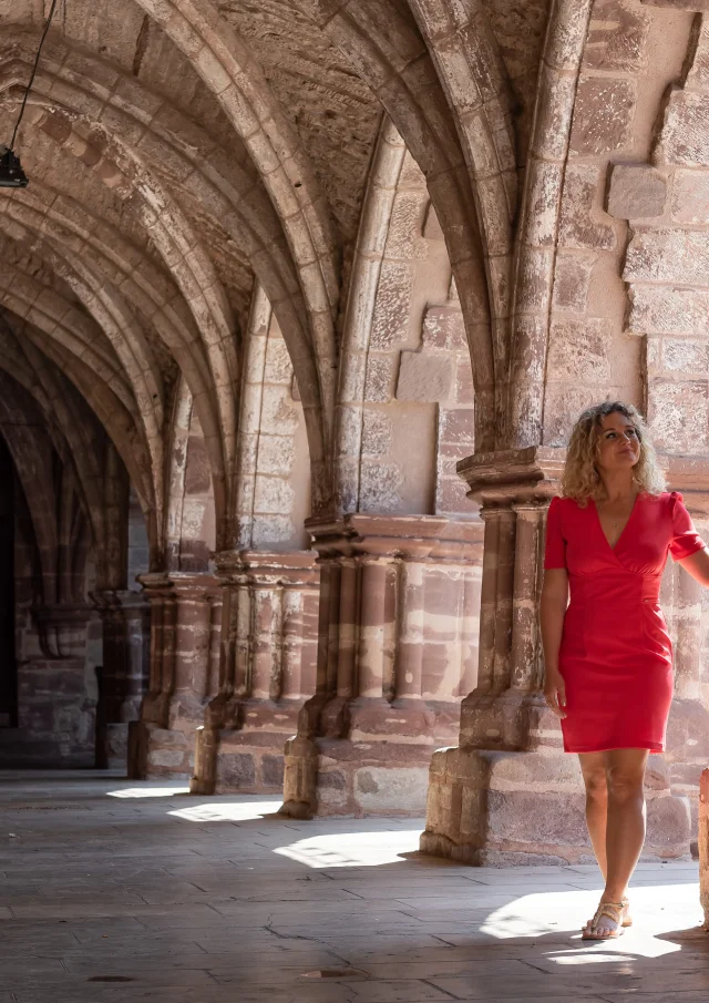 Une femme portant une robe rouge se balade dans le cloitre de Luxeuil-Les-Bains - Vosges du Sud