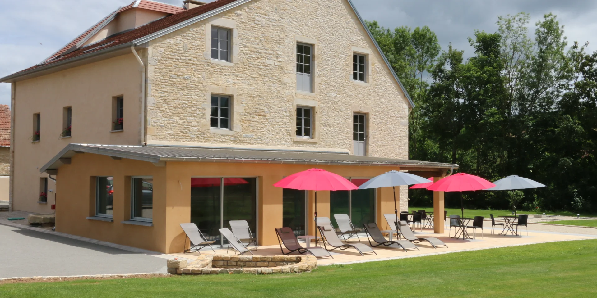Vue extérieure du Gîte de la Tourelle à Bay, avec la terrasse aménagée de bains de soleil et de parasols - Vallée de l'Ognon