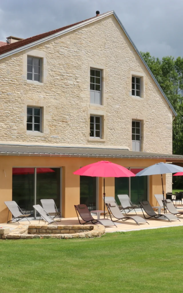 Vue extérieure du Gîte de la Tourelle à Bay, avec la terrasse aménagée de bains de soleil et de parasols - Vallée de l'Ognon