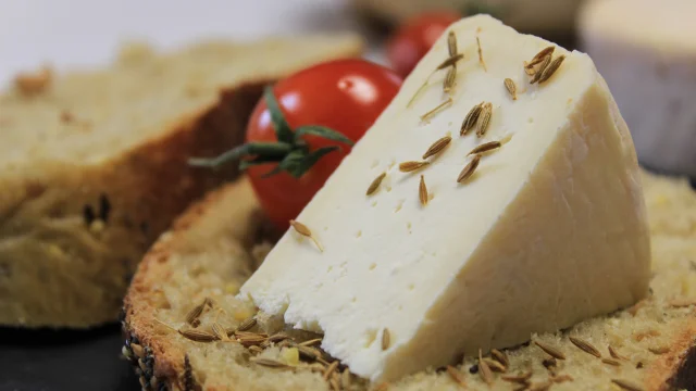 Un morceau de munster assaisonné avec du cumin sur une tranche de pain et accompagné d'une petite tomate cerise - Vosges du Sud