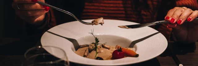 Une femme goûte un plat en sauce servi dans une grande assiette creuse - Vosges du Sud