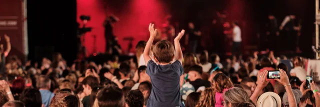 Public de festivaliers face à la scène du Rolling Saône à Gray dont un enfant qui lève les mains assis sur les épaules d'un adulte - Vesoul - Val de Saône