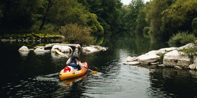 A l'automne, une femme descend la rivière Ognon en canoë et une vache l'observe en arrière-plan - Vallée de l'Ognon