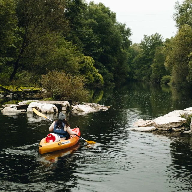 A l'automne, une femme descend la rivière Ognon en canoë et une vache l'observe en arrière-plan - Vallée de l'Ognon