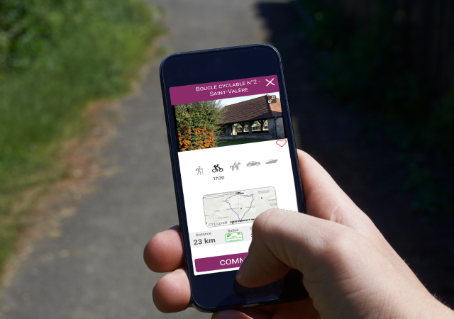 Une personne tient un smartphone avec l'application My Haute-Saône ouverte, permettant de suivre un itinéraire vélo en direct