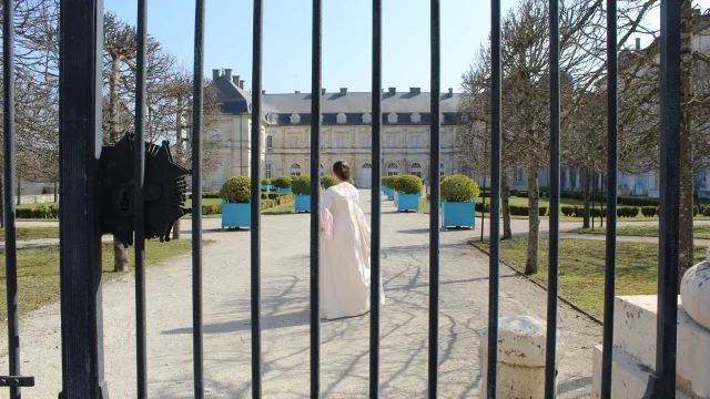 Une femme en costume d'époque arpente la cour du château de Champlitte - Escape game au château - Vesoul-Val de Saône