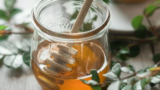 Une cuillère à miel est plongée dans un pot