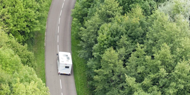 Un camping-car sillonne la route au milieu de la forêt