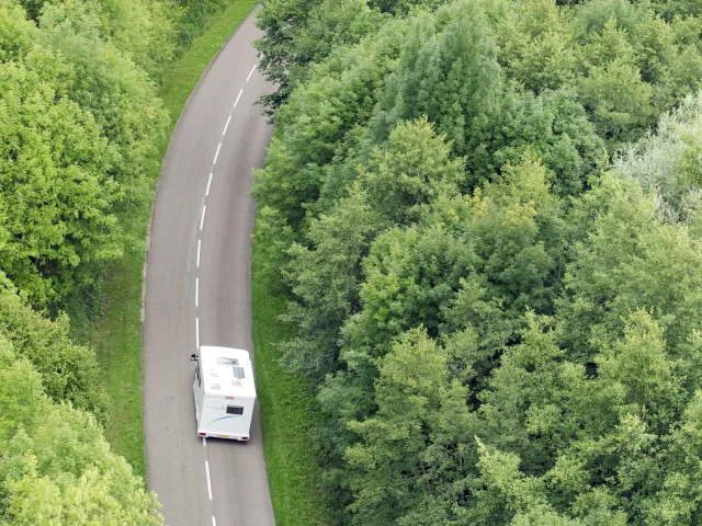 Un camping-car sillonne la route au milieu de la forêt