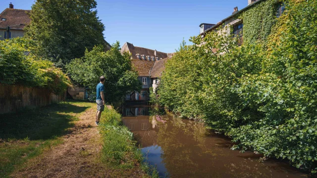 Un homme visite Faverney et découvre au cours de sa balade de belles demeures et le cours d'eau 