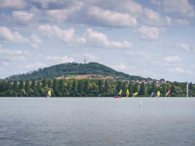 lac de Vesoul-Vaivre où l'on voit des petits bateaux à voile navigués, en arrière-plan on voit la Colline Notre-Dame de la Motte - Vesoul - Val de Saône