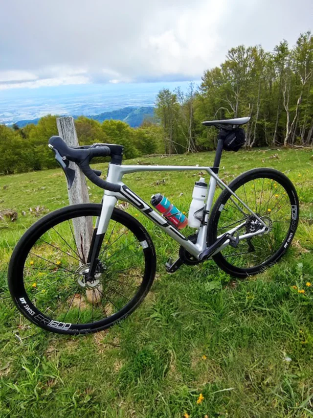 Photo d'un gravel devant un panorama de prairies, forêts et vue sur les Ballons des Vosges - Plateau des 1000 Etangs - Vosges du Sud