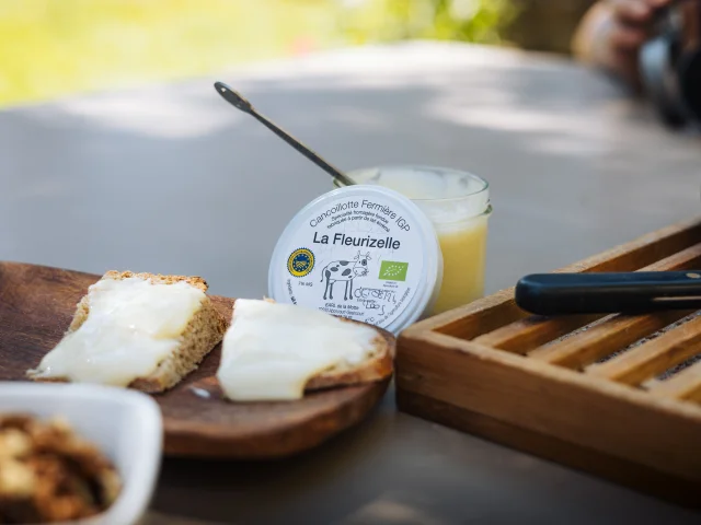 Deux tranches de pain tartinées de cancoillotte IGP sont posés sur une table, à côté d'un pot de cancoillotte IGP de la fromagerie bio La Fleurizelle à Aboncourt-Gesincourt - Vesoul-Val de Saône