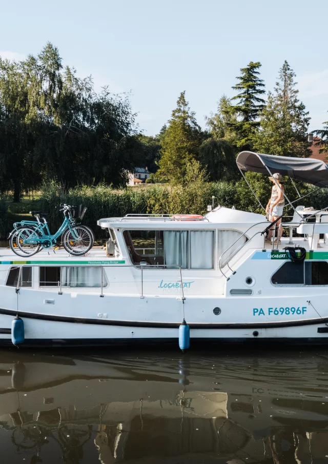 Un femme pilote un bateau sans permis sur la Saône, en admirant le paysage alentour, en pleine nature préservée - Vesoul-Val de Saône