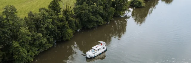 Vue aérienne d'un bateau sans permis navigant sur la Saône, dans un cadre de nature préservée, au milieu de la verdure - Vesoul-Val de Saône