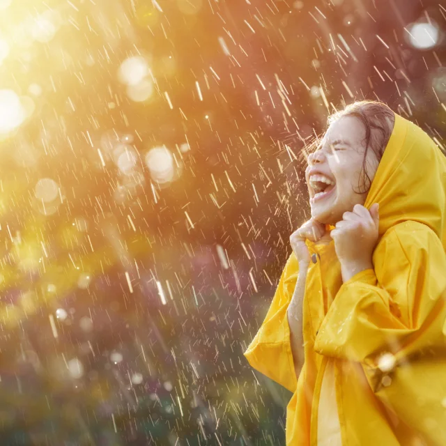 Une petite fille en ciré jaune rit sous la pluie