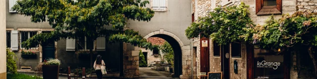 Une femme déambule dans les rues de Marnay, à sa droite se trouve le magasin de thé et café laGrange - Vincent Ballot - Barbara Bessot Ballot - Cité de Caractère - Vallée de l'Ognon