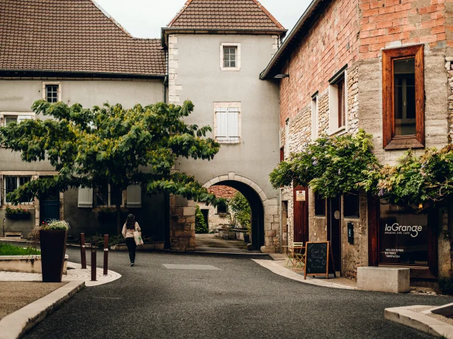 Une femme déambule dans les rues de Marnay, à sa droite se trouve le magasin de thé et café laGrange - Vincent Ballot - Barbara Bessot Ballot - Cité de Caractère - Vallée de l'Ognon