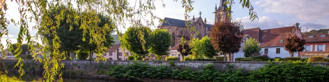 Une femme et un homme pêche dans le Rahin à Ronchamp. À l'arrière-plan, on observe la commune avec son église Notre-Dame du Bas - Vosges du Sud