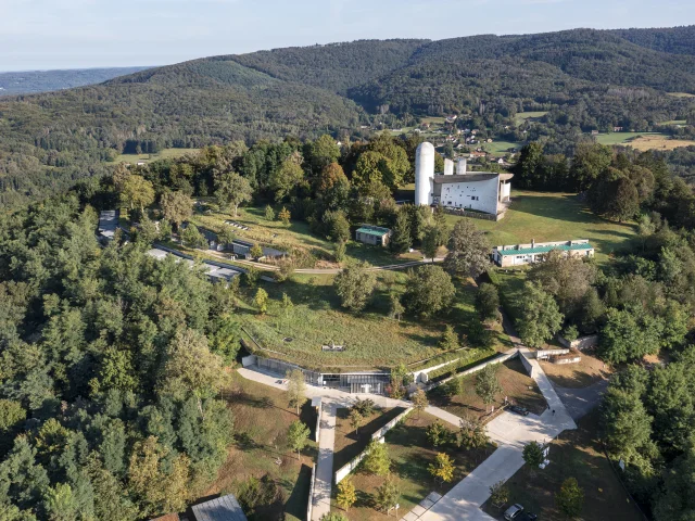 Vue aérienne de la Colline Notre-Dame du Haut, où l'on peut voir La Chapelle Le Corbusier, l'abri du pèlerin, la maison du chapelain. La Porterie et le monastère Sainte-Claire de Renzo Piano sont également visibles - Vosges du Sud