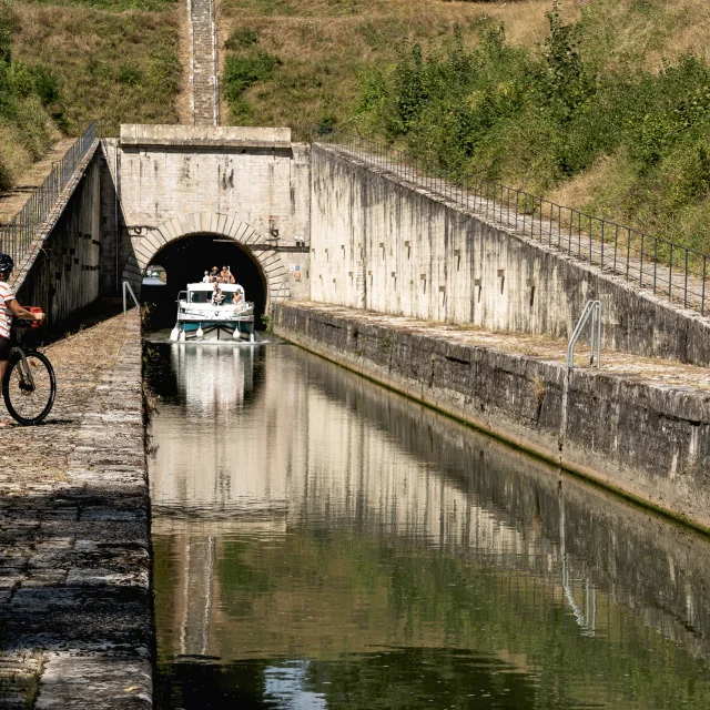 Cycliste observant un bateau naviguant sur la Saône, à la sortie du tunnel de Seveux, sur La Voie Bleue - Vesoul-Val de Saône