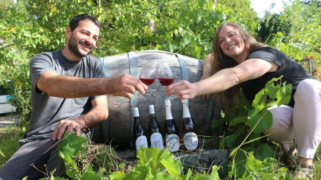 Lucie et Vincent du Vignoble Cheviet posent devant un tonneau, dans les vignes et devant des bouteilles de vin issues de leur production - Vallée de l'Ognon, Haute-Saône