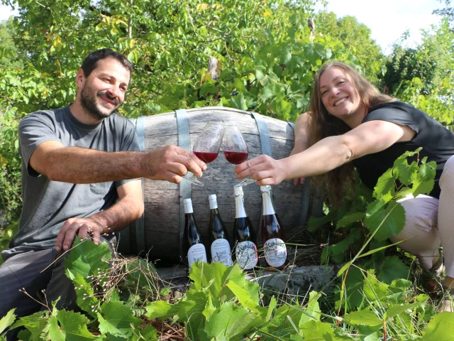 Lucie et Vincent du Vignoble Cheviet posent devant un tonneau, dans les vignes et devant des bouteilles de vin issues de leur production - Vallée de l'Ognon, Haute-Saône