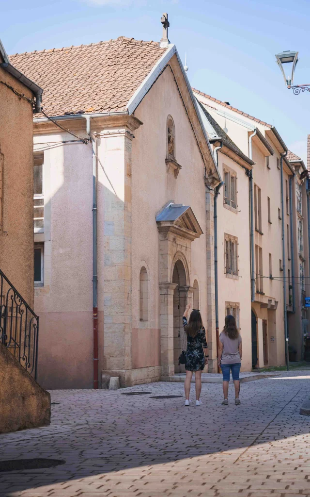 Deux femmes se promènent dans les rues pavées de Vesoul. Il y observe un bâtiment religieux en pierre - Vesoul - Val de Saône