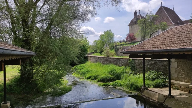 La rivière La rivière la filaine traverse la Cité de Caractère de Filain. En arrière-plan on aperçoit les premiers éléments architecturaux du château - Vallée de l'Ognon