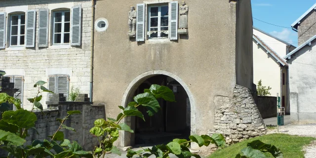 Détail d'une maison d'époque avec une fenêtre entourée de deux sculptures, un homme et une femme, dans la Cité de Caractère de Villersexel - Vallée de l'Ognon