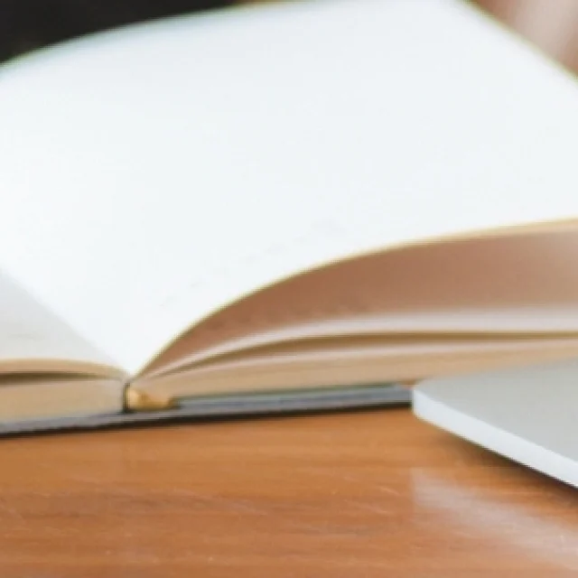 Une femme travaille sur un PC et prend des notes sur un carnet - Audit d'outils digitaux par Destination 70