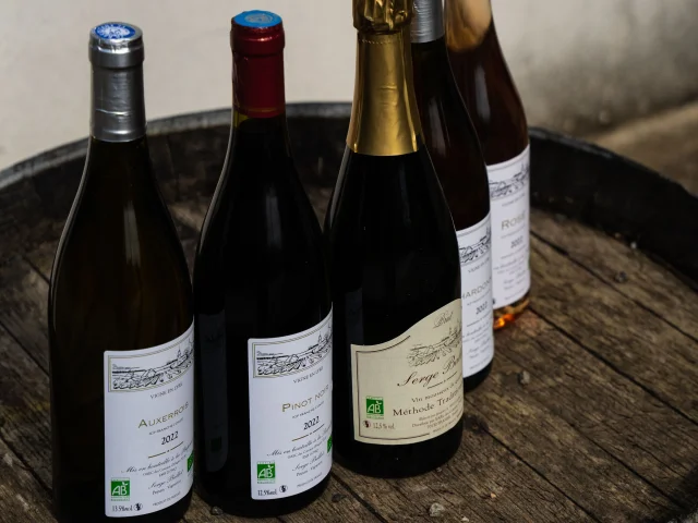 Assortiment de bouteilles de vins du domaine Les Coteaux d'Hugier posé sur un tonneau en bois - Vallée de l'Ognon