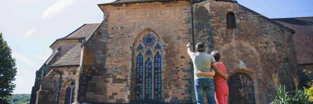 Un couple regarde l'église abbatiale de Faverney. L'homme pointe du doigt le clocher - Vesoul - Val de Saône