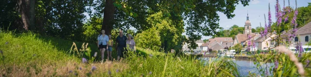 Une famille se balade en bord de Saône. On aperçoit en arrière-plan la ville de Port-sur-Saône, son église et des bateaux - Vesoul - Val de Saône