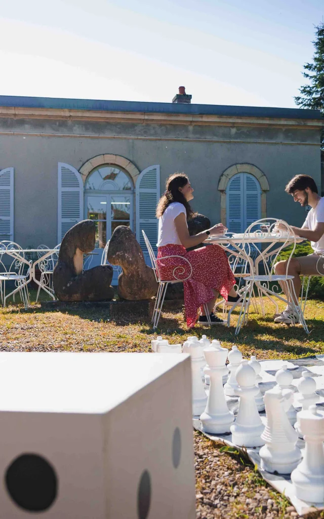 Un couple déjeune en terrasse au Musée Baron Martin. Au premier-plan, on voit un jeu d'échec de grande taille - Gray - Cité de caractère - Vesoul - Val de Saône