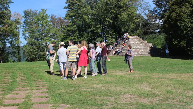 Des touristes assistent à une visite guidée de la Colline Notre-Dame du Haut, en arrière-plan on voit 