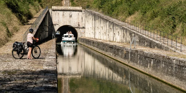 Cycliste observant un bateau naviguant sur la Saône, à la sortie du tunnel de Seveux, sur La Voie Bleue - Vesoul-Val de Saône