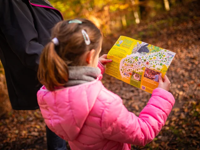 Une jeune fille tient dans ses mains le plan du Parc animalier de Fougerolles - Vosges du Sud