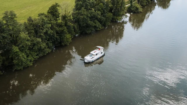 Vue aérienne d'un bateau sans permis navigant sur la Saône, dans un cadre de nature préservée, au milieu de la verdure - Vesoul-Val de Saône