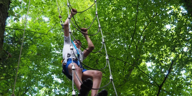 Un adolescent grimpe à l'échelle à Accro'Rioz, un parcours d'accrobranche situé dans la Cité de Caractère de Rioz - Vallée de l'Ognon