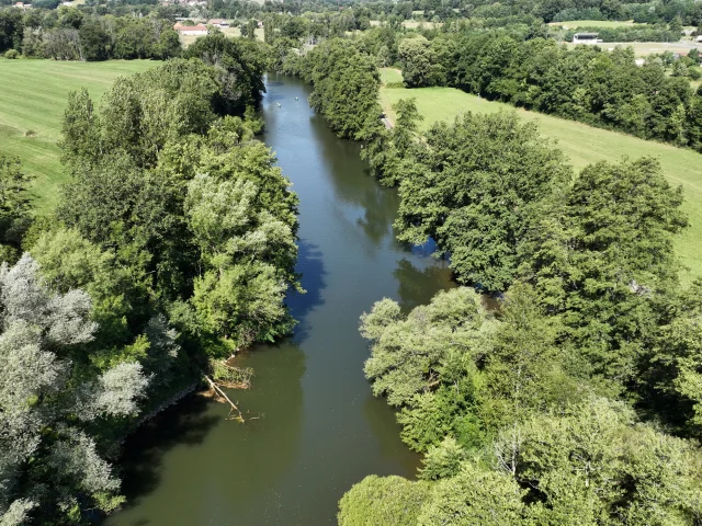 Vue aérienne de la rivière Ognon entourée de nature : forêts et prairies. Au loin on perçoit deux canoë-kayak qui descendent la rivière - Vallée de l'Ognon